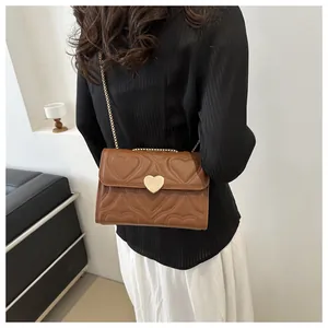 Brown crossbody bag with heart-shaped stitching and chain strap on female model