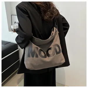 Hobo canvas bag with MOOD lettering detail and adjustable wide shoulder strap shown on model