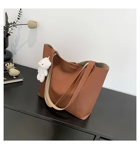 Detailed macro of caramel brown tote bag featuring lychee texture and soft plush charm