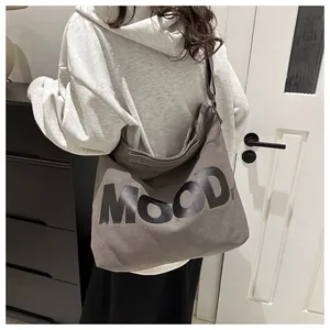 Rear view of a model wearing a grey canvas tote bag with MOOD lettering print