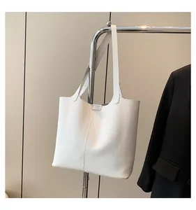 Detail view of white pebbled leather tote bag hanging next to a black office blazer