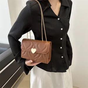 Brown heart quilted crossbody bag with gold chain strap and heart lock on model