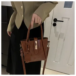 Brown vintage leather bucket bag with gold clasp and adjustable strap worn by a model