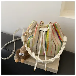 Detail of beige canvas bucket bag with colored stitching and cute monster charm