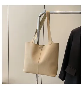 Detail of beige lychee textured leather tote bag with buckle closure on a hanger