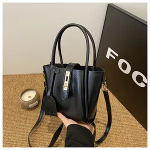 Detail of black water bucket bag with glossy leather texture and gold twist lock closure