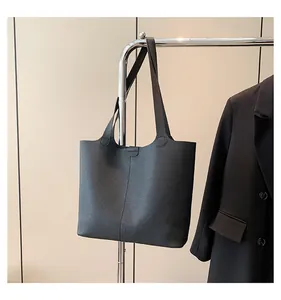 Detailed view of black pebbled leather tote bag hanging with professional business suit
