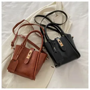 Detailed view of leather bucket bags in brown and black with gold metal buckles