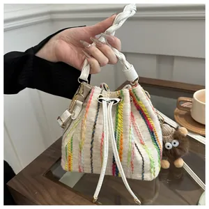 Detail of colorful woven stripes on a cream bucket bag with a cute plush charm