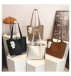 Detailed view of four minimalist faux leather tote bags with cute bear charms on pedestals