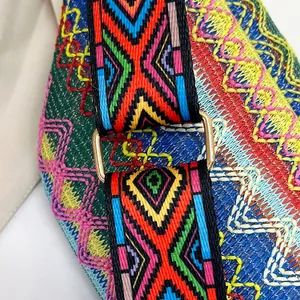 Detailed macro view of colorful ethnic embroidery and gold metal buckle on a crossbody bag