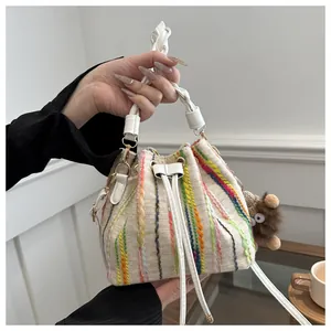 Detail of woven bucket bag with colorful vertical stitching and cute bear charm