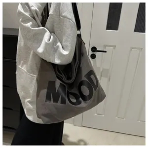 Detail of grey canvas tote bag featuring MOOD lettering with wide shoulder strap