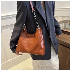 Vue détaillée du sac à bandoulière en similicuir caramel avec chaîne dorée et logo gravé