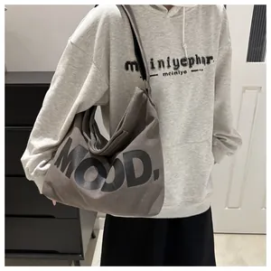 Detail of grey canvas crossbody bag with MOOD lettering worn by a casual model