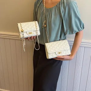 White quilted crossbody bag with gold chain strap and metal turn-lock closure for women