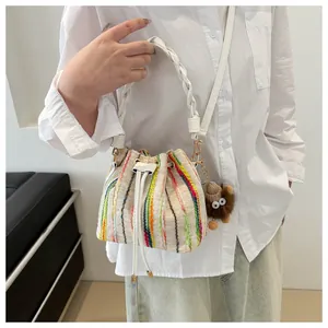 Close-up of woven bucket bag with colorful vertical stripes and cute brown plush charm