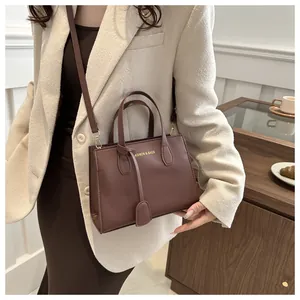 Detailed view of brown faux leather tote bag featuring gold lettering and sturdy handles