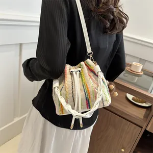 Chic woven drawstring bucket bag with colorful stripes and leather shoulder strap
