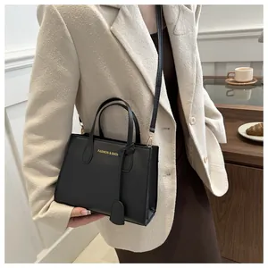 Chic black structured handbag with gold text detail and adjustable shoulder strap for casual wear