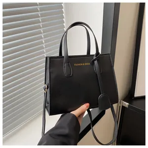Close-up of black PU leather square bag with golden logo and adjustable strap detailing
