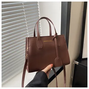 Detail of caramel leather square bag with gold Fashion & Bags logo and shoulder strap