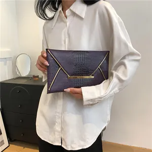Elegant deep purple envelope clutch bag featuring crocodile pattern leather and gold V-shaped metal trim