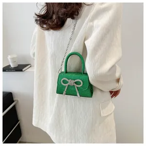 Détail du sac bandoulière vert pailleté avec nœud en strass et franges argentées