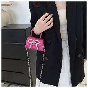 Détail du mini sac à paillettes rose fuchsia avec nœud argenté et chaîne métal