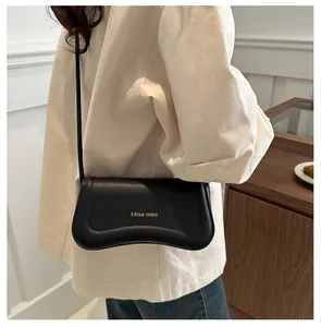 Detail of black leather shoulder bag featuring a wave-edge flap and Miss mini gold lettering