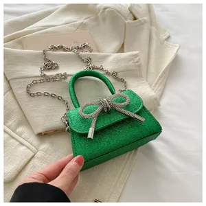 Détail du sac à paillettes vertes avec un grand nœud en strass et sa chaîne argentée