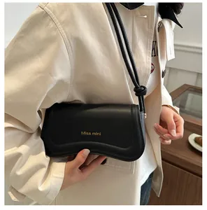 Detail of black leather crossbody bag with wave flap design and Miss mini gold lettering