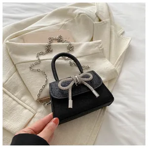 Détail du mini sac noir scintillant avec nœud en strass et fine bandoulière chaîne