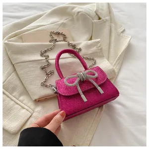 Détail d'un mini sac rose à paillettes avec nœud strass et bandoulière chaîne