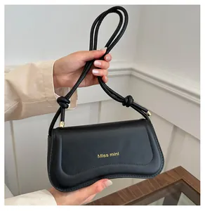 Detail of a chic black matte leather mini shoulder bag with gold Miss mini logo and knotted strap