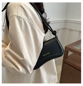 Detailed view of the black leather underarm bag with gold Miss mini logo on model