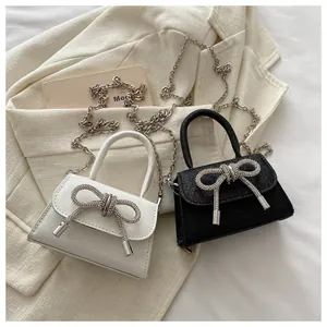 Gros plan de mini sacs à main pailletés avec nœud en strass sur fond de veste chic