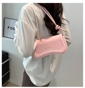 Close-up of pink faux leather shoulder bag with wavy bottom and gold Miss Mini logo