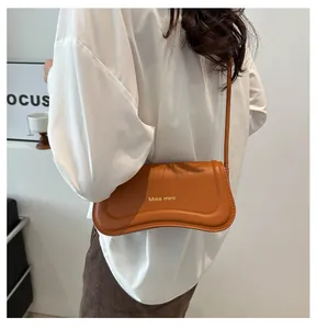 Detail of caramel brown mini shoulder bag with Miss mini logo and slim strap on model