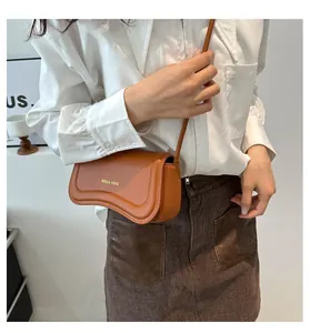 Detail of caramel crescent crossbody bag with Miss Mini gold lettering and smooth leather