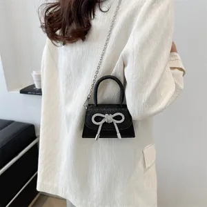 Petit sac bandoulière noir brillant avec nœud en strass et chaîne argentée élégante