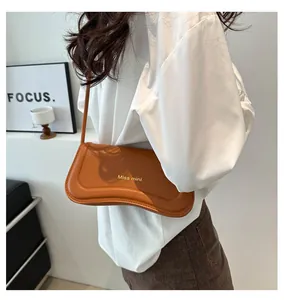Detail of an orange-brown leather underarm bag with gold Miss Mini text and sleek strap