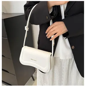 Detail view of a white leather underarm bag with curved bottom and knot strap detail