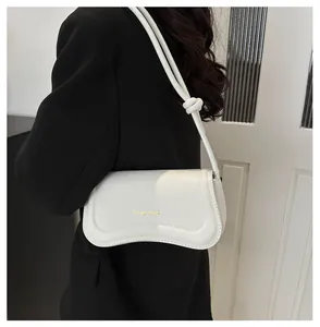 Detail of white mini underarm bag with gold logo and minimalist strap on black blazer