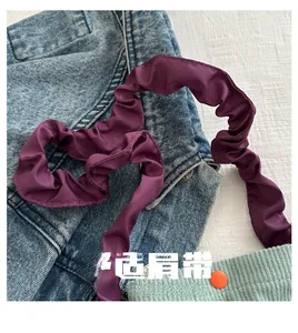 Detail of a purple pleated strap with blue denim and green corduroy fabric textures