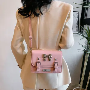 Pink bow fashion crossbody bag with flap and metal hardware shown on model