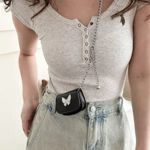 Mini black bow accent crossbody bag with silver chain strap shown on model stylishly
