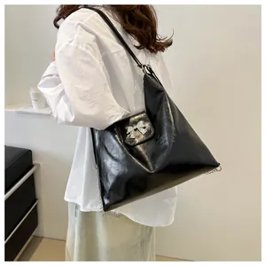 Détail du sac cabas en cuir verni noir brillant orné d'un nœud métallique argenté