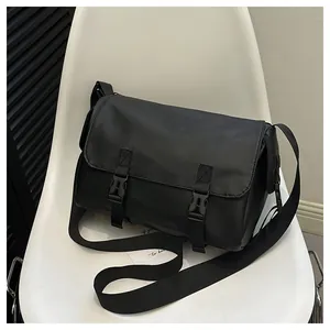 Détail d'un sac messager en nylon noir avec deux boucles en plastique sur une chaise