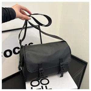 Détail du sac messager en nylon noir avec fermeture à boucle et bandoulière réglable